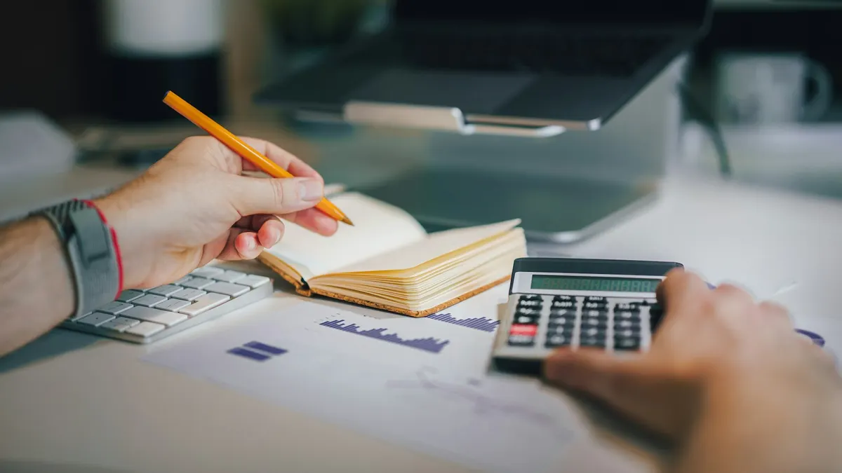 Un cuaderno, un lápiz y una calculadora sobre un escritorio