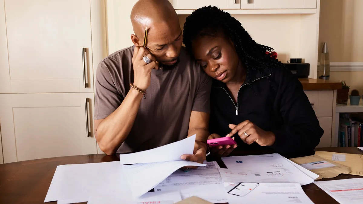 A couple at a kitchen table going through a pile of bills and letters